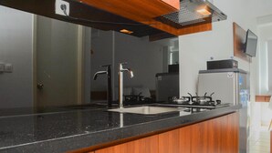 A modern kitchen with a black countertop, stainless steel appliances, and wooden cabinets.