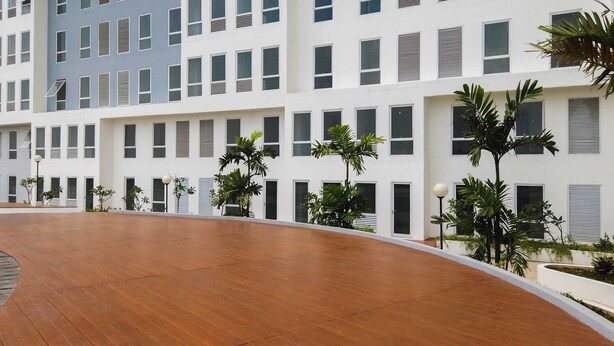 A modern building with a flat roof, multiple windows, and a central courtyard with a wooden floor.