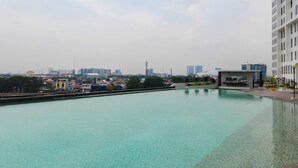 A swimming pool with clear water, surrounded by a high-rise building and other urban structures in the background.