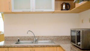 A kitchen with a granite countertop, stainless steel sink, and a microwave. - Modern 2BR at The Belleza Apartment (Jakarta)