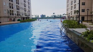 A swimming pool surrounded by modern apartment buildings. - Cozy Studio Apartment at Ayodhya Residences By Travelio (Tangerang)