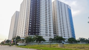 A high-rise residential building with multiple floors, a flat facade, and a uniform window pattern. - Cozy Studio Apartment at Ayodhya Residences By Travelio (Tangerang)