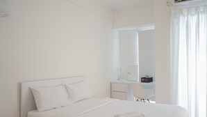 A modern hotel room with a neatly made bed, a desk with a chair, and a large window with curtains. - Cozy Studio Apartment at Ayodhya Residences By Travelio (Tangerang)