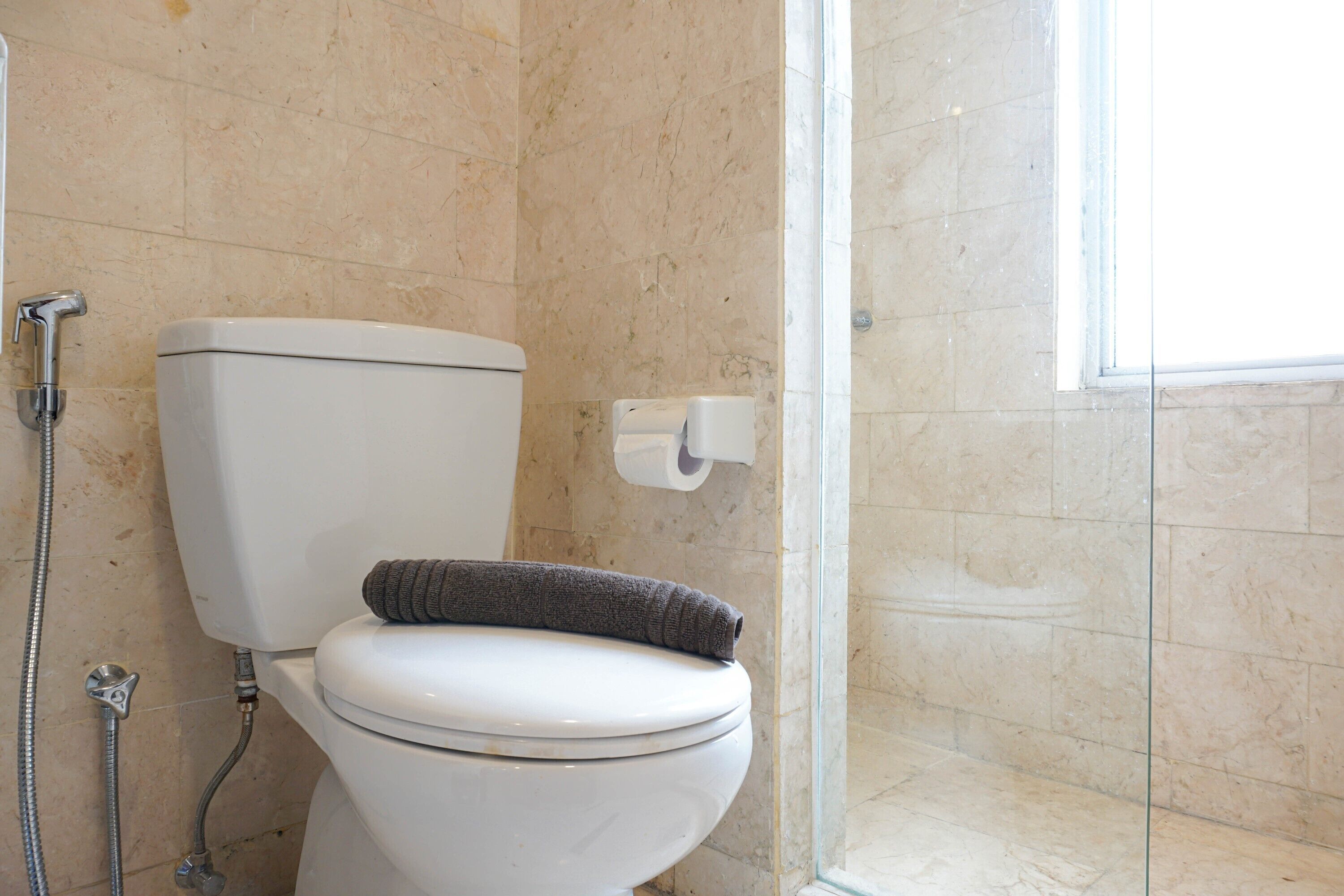 A bathroom with a toilet, a shower, and a glass door leading to a shower area.