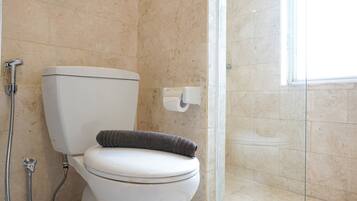 A bathroom with a toilet, a shower, and a glass door leading to a shower area.