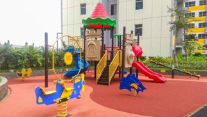 A playground with a slide, swings, and a climbing structure. - Cozy with City View @ Studio Springlake Bekasi Apartment By Travelio (Bekasi)