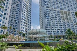 A modern hotel with high-rise buildings, a glass atrium, and a pool area. - Modern with City View @ Studio Puri Mansion Apartment By Travelio (Jakarta)