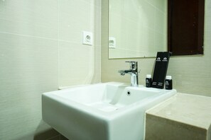 A bathroom with a white sink, a mirror, and two toothbrushes on the counter. - Modern with City View @ Studio Puri Mansion Apartment By Travelio (Jakarta)