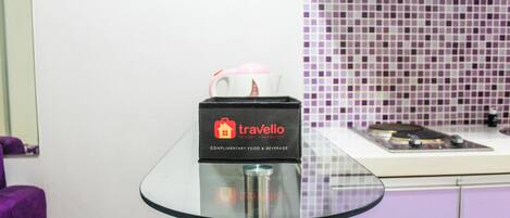 A glass-top table with a box labeled "travelio" and a pink mug on it.