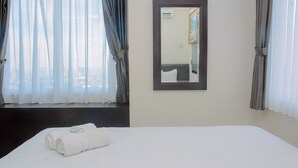 A hotel room with a neatly made bed, a large mirror, and a view through the window. - Strategic Location 2BR Apartment at FX Residence By Travelio (Jakarta)