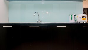 A modern kitchen with a stainless steel faucet, a kettle, and a coffee maker on the counter. - Comfy and Spacious 2BR The Masterpiece Epicentrum Apartment By Travelio (Jakarta)