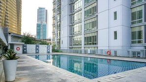 A swimming pool with a tiled edge, surrounded by a concrete deck and a white fence. - Comfortable Deluxe 2BR at The Empyreal Condominium Epicentrum Apartment By Travelio (Jakarta)