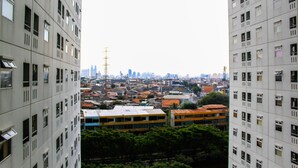 A high-rise building with multiple windows and balconies, surrounded by other buildings and greenery. - Comfortable and Tranquil 2BR Apartment at Green Pramuka By Travelio (Jakarta)
