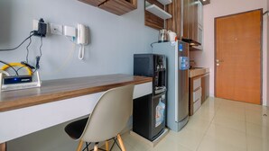 Una cocina con encimera de madera, microondas, refrigerador y dispensador de agua. Hay una silla y un teléfono sobre la encimera.