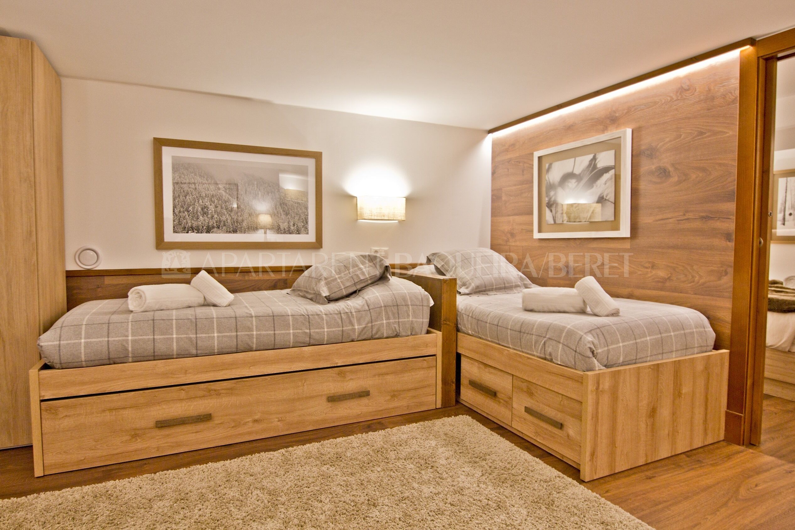 Ein Schlafzimmer mit zwei hölzernen Betten, einem großen Spiegel und gerahmten Kunstwerken an den Wänden.