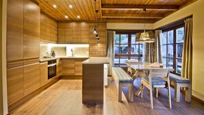 Una cocina moderna con armarios de madera, una isla central y una zona de comedor con banco y mesa.