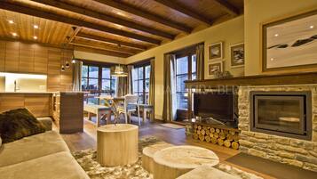 A spacious living area with a stone fireplace, wooden ceiling beams, and a cozy seating arrangement.