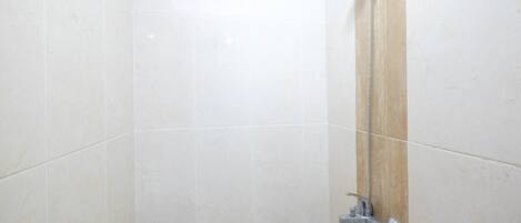 A bathroom with white tiles, a showerhead, and a handheld shower attachment.