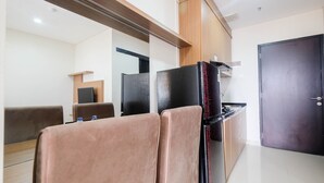 A modern kitchen with a refrigerator, wooden cabinets, and a dark door. - Warm and Homey 1BR Apartment at Atlanta Residences By Travelio (Depok)