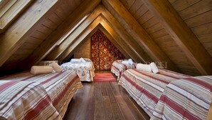 A cozy attic bedroom with two beds, wooden beams, and a floral curtain. - Sendrosa - Val de Ruda (Baqueira)