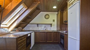 A kitchen with wooden cabinets, a white refrigerator, and a clock on the wall. - Sendrosa - Val de Ruda (Baqueira)