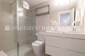 Une salle de bain moderne avec une douche à parois de verre, des toilettes blanches et un meuble-lavabo avec un miroir.