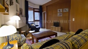 A living room with a sofa, a coffee table, a lamp, a TV, and a window with curtains.