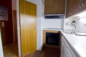 A compact kitchen with wooden cabinets, a dishwasher, and a built-in oven.