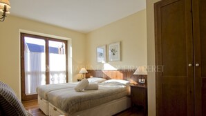 A bedroom with a bed, bedside tables, a chair, a wardrobe, and a window with curtains. - Solana - Pleta de Nheu (Naut Aran)