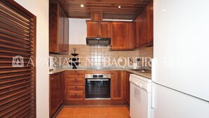 A kitchen with wooden cabinets, a built-in oven, and a dishwasher. - Solana - Pleta de Nheu (Naut Aran)