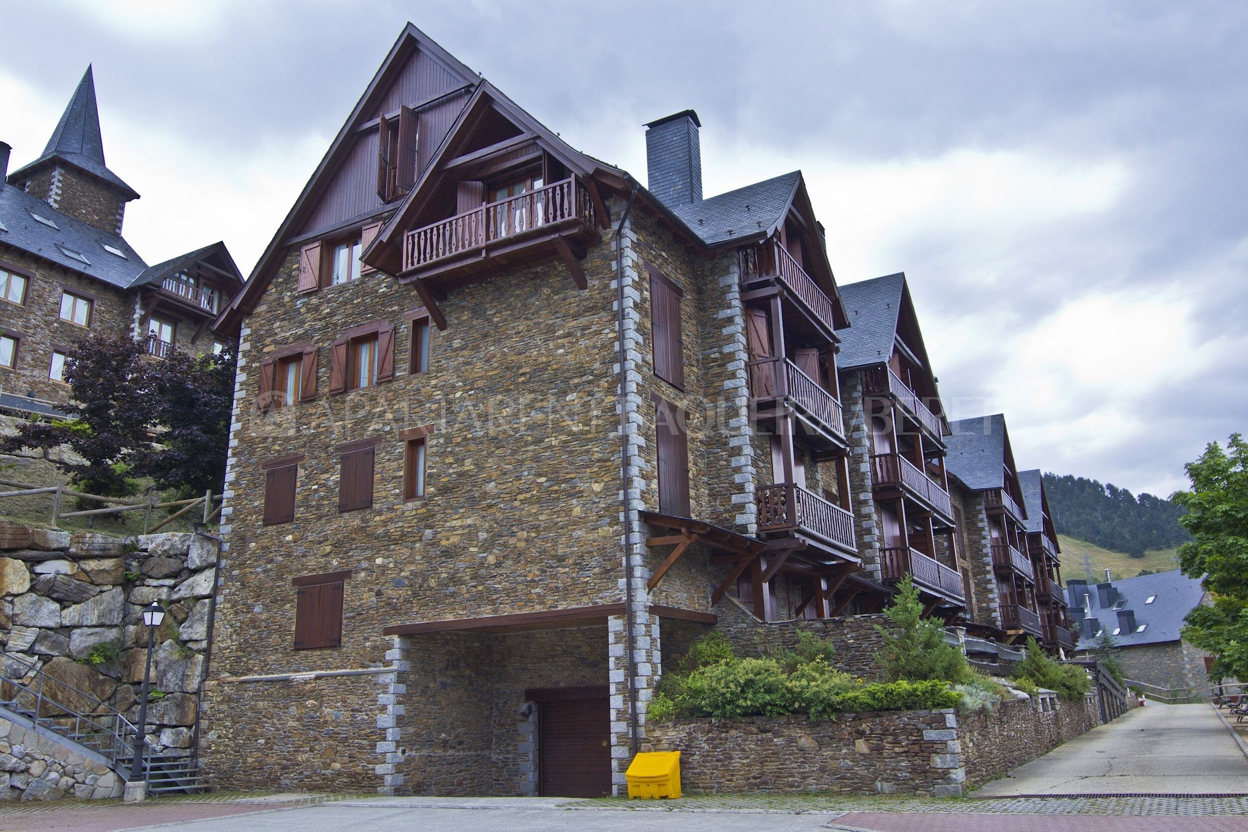 Un edificio de piedra con varios balcones y un techo inclinado, probablemente un hotel o una posada.