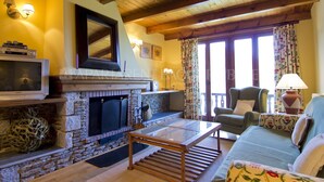 A cozy living room with a stone fireplace, a television, and a comfortable seating area. - Azor - Pleta de Nheu (Naut Aran)