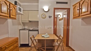 Cocina compacta con muebles de madera, un microondas y una mesa de comedor con sillas.