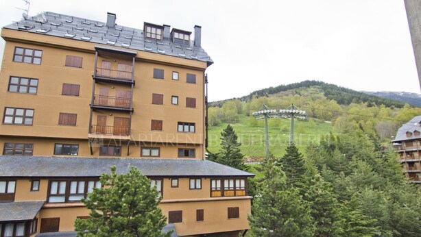 Un hotel de varios pisos con balcones y vistas a una colina verde.
