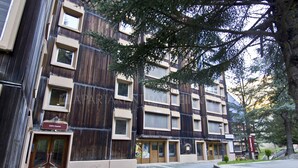 A multi-story building with a modern design, featuring a mix of dark and light wood paneling. There is a sign indicating a restaurant on the ground floor.