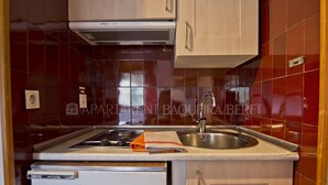 A kitchen with a stove, sink, and white refrigerator.