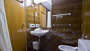 A bathroom with a sink, toilet, and bidet. There are two soap dispensers on the wall.