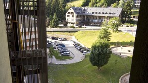 A hotel with a parking lot, a grassy area, and a building with multiple windows and a sloped roof. - Garona - Edificio Aneto (Baqueira)