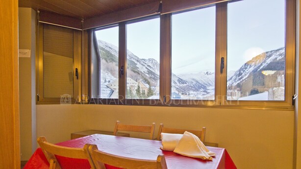 Un coin repas avec une table dressée pour quatre personnes, de grandes fenêtres offrant une vue sur des montagnes enneigées et un panneau indiquant qu’il s’agit d’une salle privée.