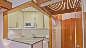Une cuisine de taille réduite, équipée d’un four à micro-ondes, d’un évier et de meubles de rangement en bois.