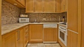 Una cocina con gabinetes de madera, microondas, lavavajillas y horno.