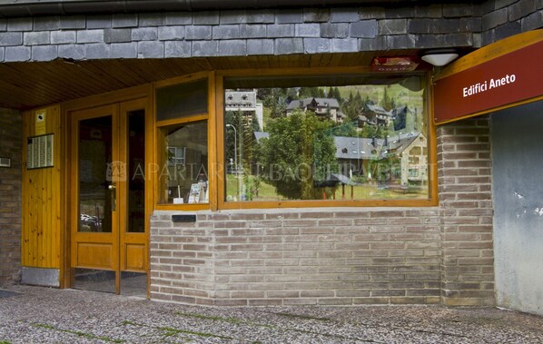 En byggnad med en trädörr och träfönster, märkt med texten ”Edifici Aneto”.