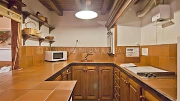 Een keuken met houten kastjes, een magnetron en een spoelbak.
