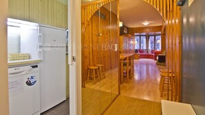 A modern kitchen with a dishwasher and a refrigerator. There is a wooden dining area with a table and chairs. - Irissa - Edificio Campalias (Baqueira)