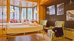 A wooden cabin-style room with a bed, two armchairs, and a view through large windows. - Irissa - Edificio Campalias (Baqueira)