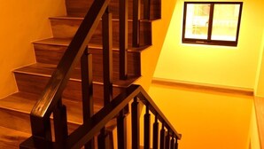 A wooden staircase with a black handrail leading to a landing with a small window. - Shui Yifang B&B (Magong)