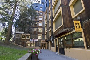 Um edifício de vários andares com fachada de madeira, um letreiro com 'RE FU BIRBERIA' e um letreiro com 'SKIURGENT'.