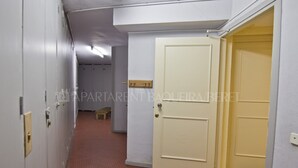 Un pasillo con casilleros, una puerta cerrada y un banco pequeño.