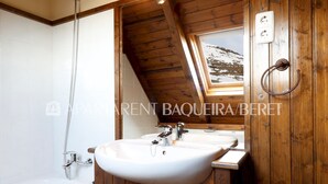 A bathroom with a wooden ceiling, a white sink, and a bathtub. - Cumbres - Nin de Beret (Baqueira)