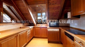 A kitchen with wooden cabinets, a microwave, and a dishwasher. - Cumbres - Nin de Beret (Baqueira)